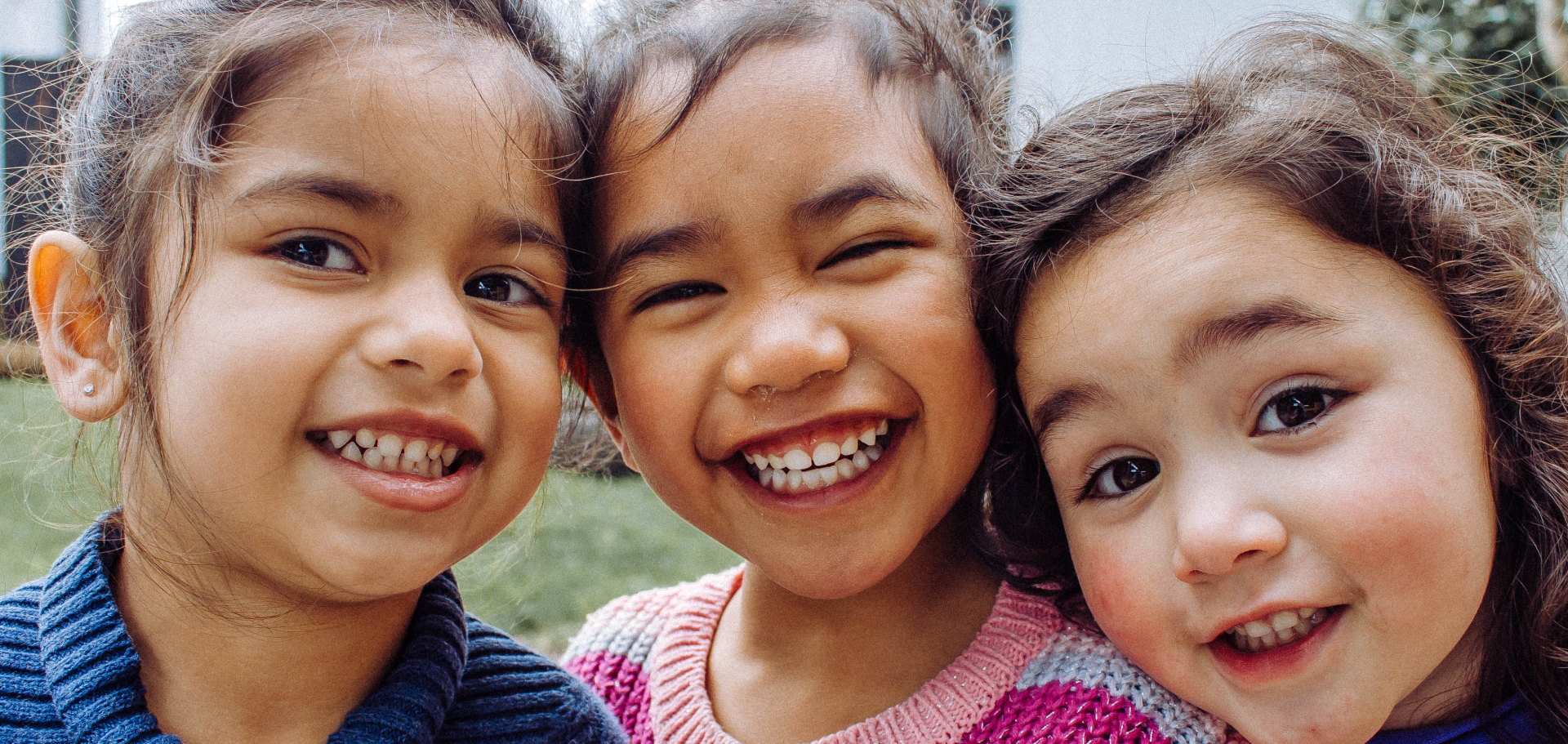 Three happy, smiling kids with their heads together.